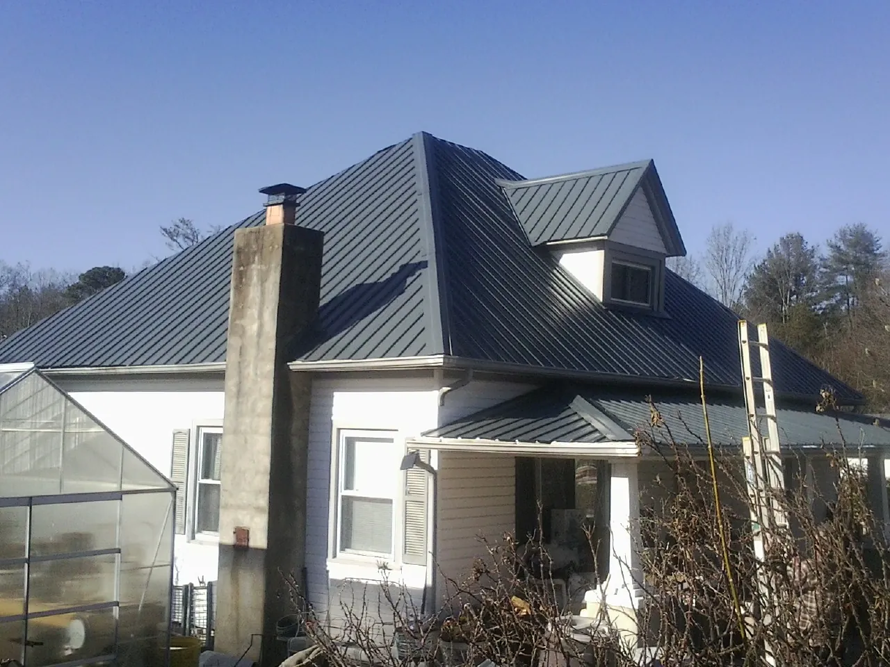 Dark blue standing seam metal roof on a white farmhouse with dormer — Slate & Tile Roof Repair by Roofing Brothers in Brewer