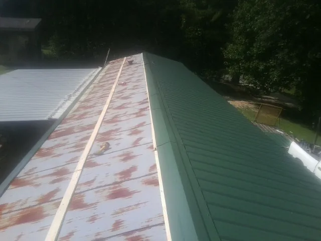 Old rusted panels beside newly installed green metal roofing — Wind Damage Roof Repair by Roofing Brothers in Brewer