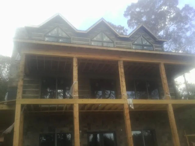 Dormers and porch framing on a large log home under construction — Roof Coating work by our crew in Brewer