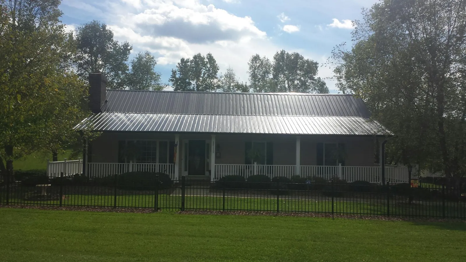 Gray metal roof on a brick ranch with a full width front porch — Gutter Guard Installation work by our crew in Brewer