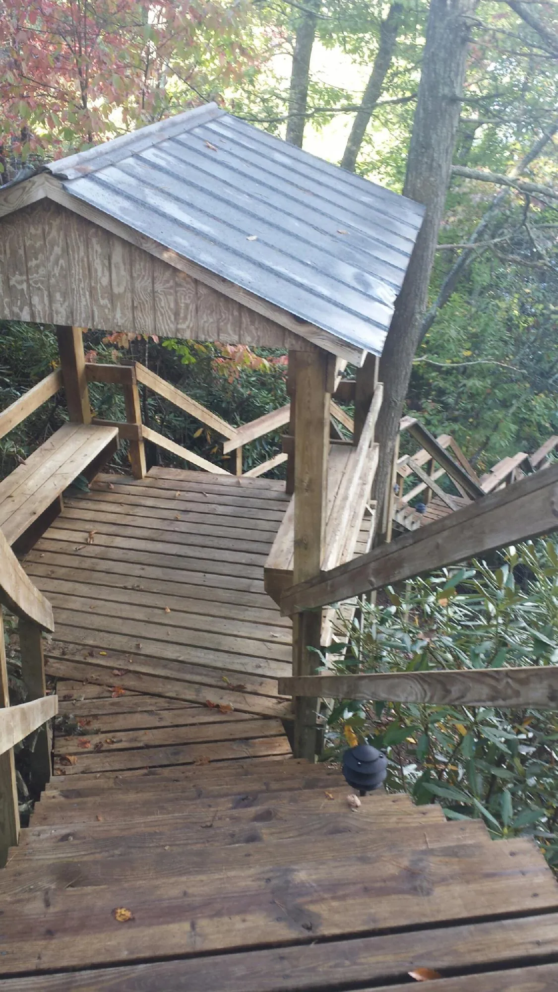 Metal roofed shelter over wooden steps on a wooded walkway — Skylight Repair & Installation work by our crew in Brewer